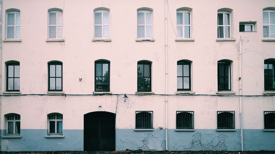 Exterior wall of a painted house with symmetrical windows.