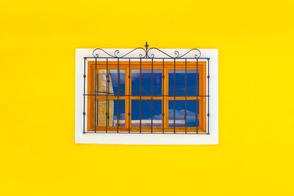A small wood-framed window set in a yellow painted wall.