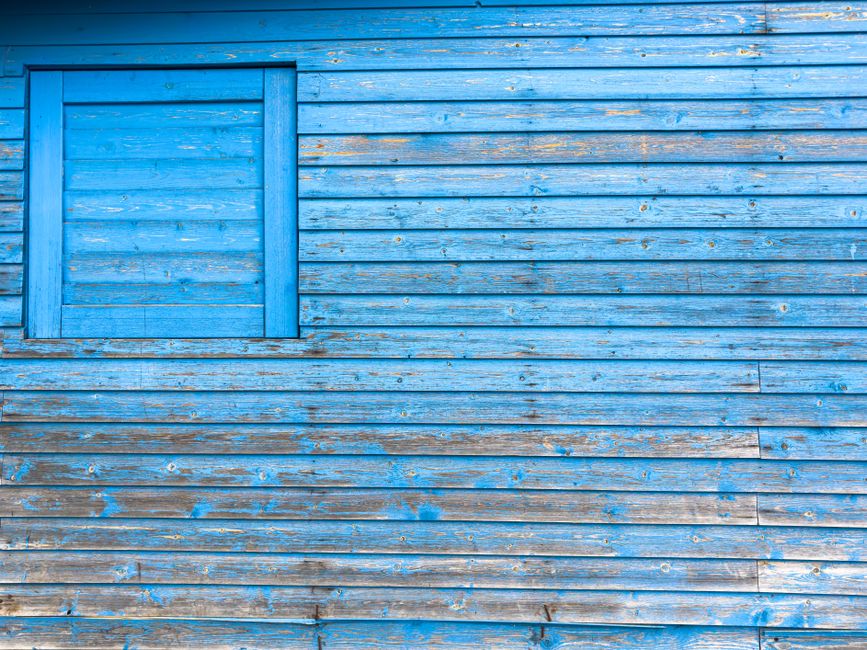 Close-up of a blue wooden wall with peeling paint.
