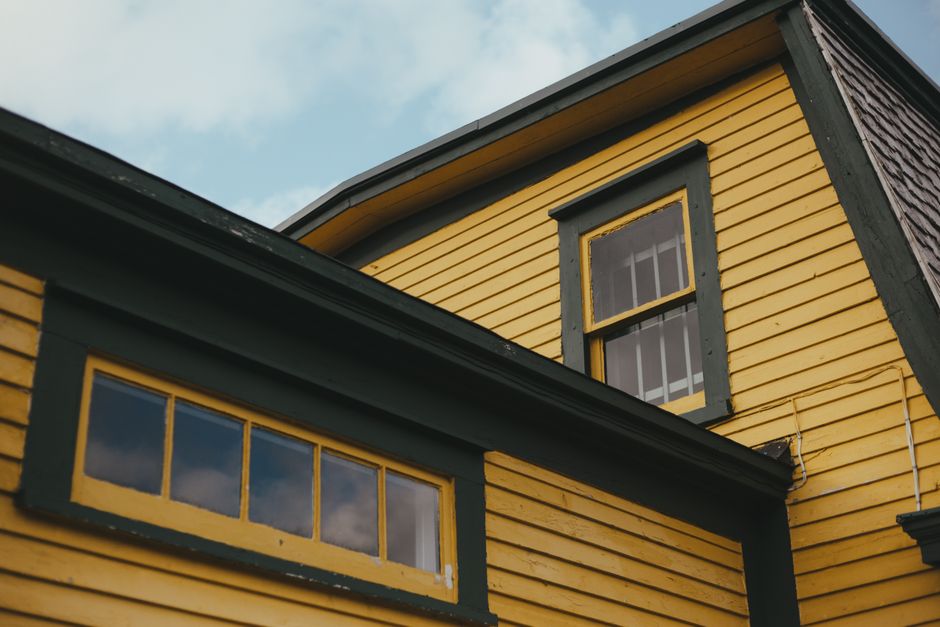 A yellow house with green trim seen from a low angle.